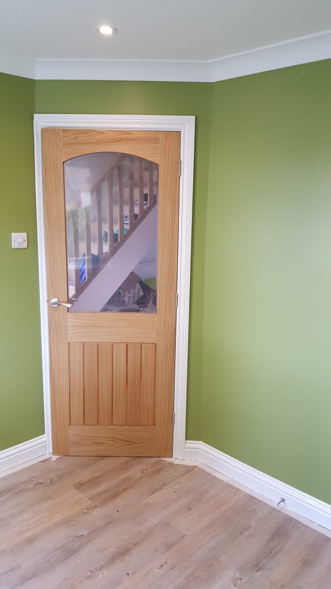 Bedroom with a part-glazed oak door and green walls
