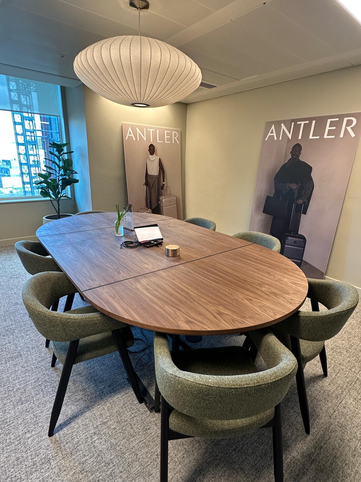 Meeting room with a walnut boardroom table and sage-green walls