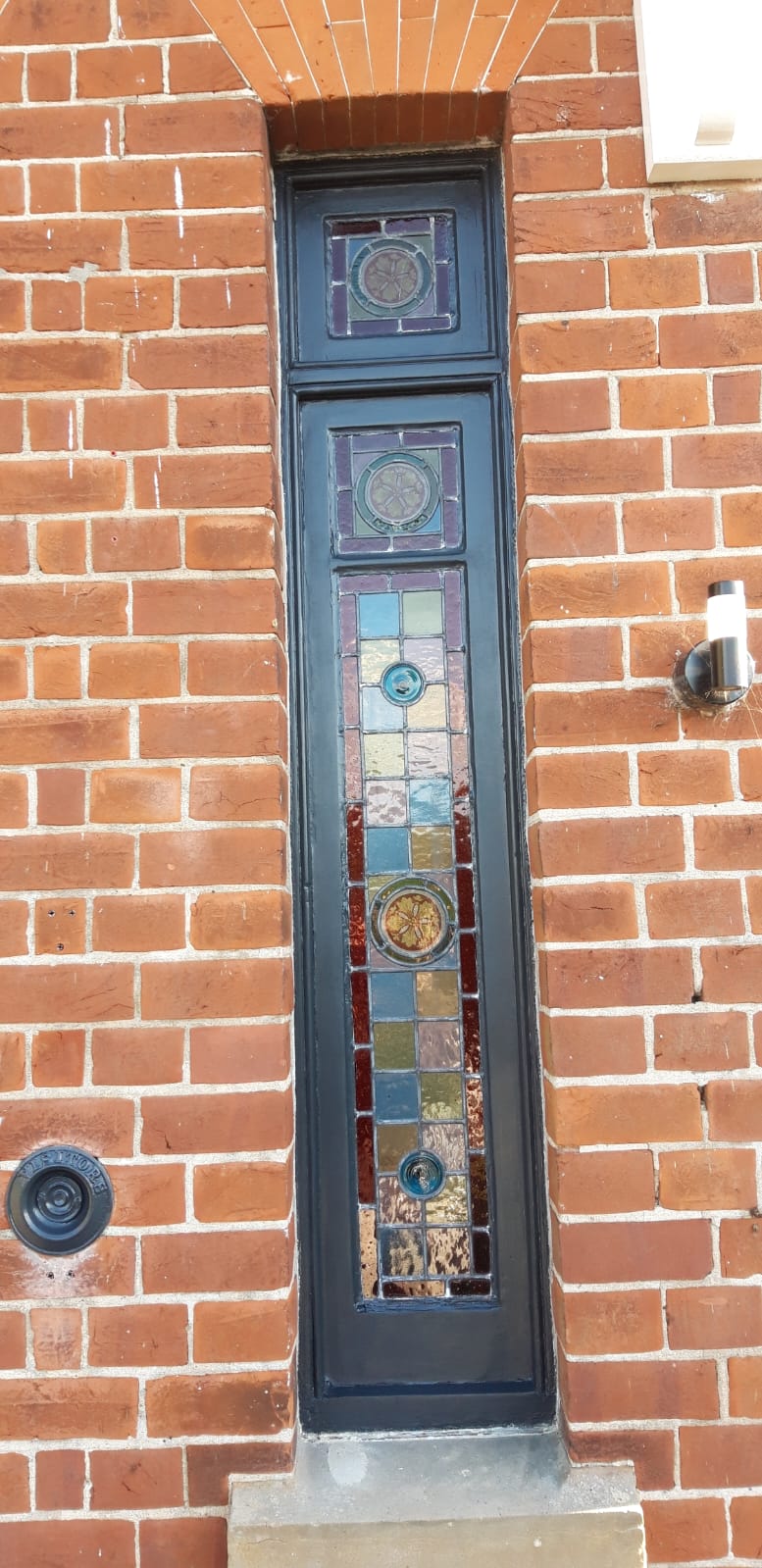 Restored stained-glass entrance sidelight set into the brickwork