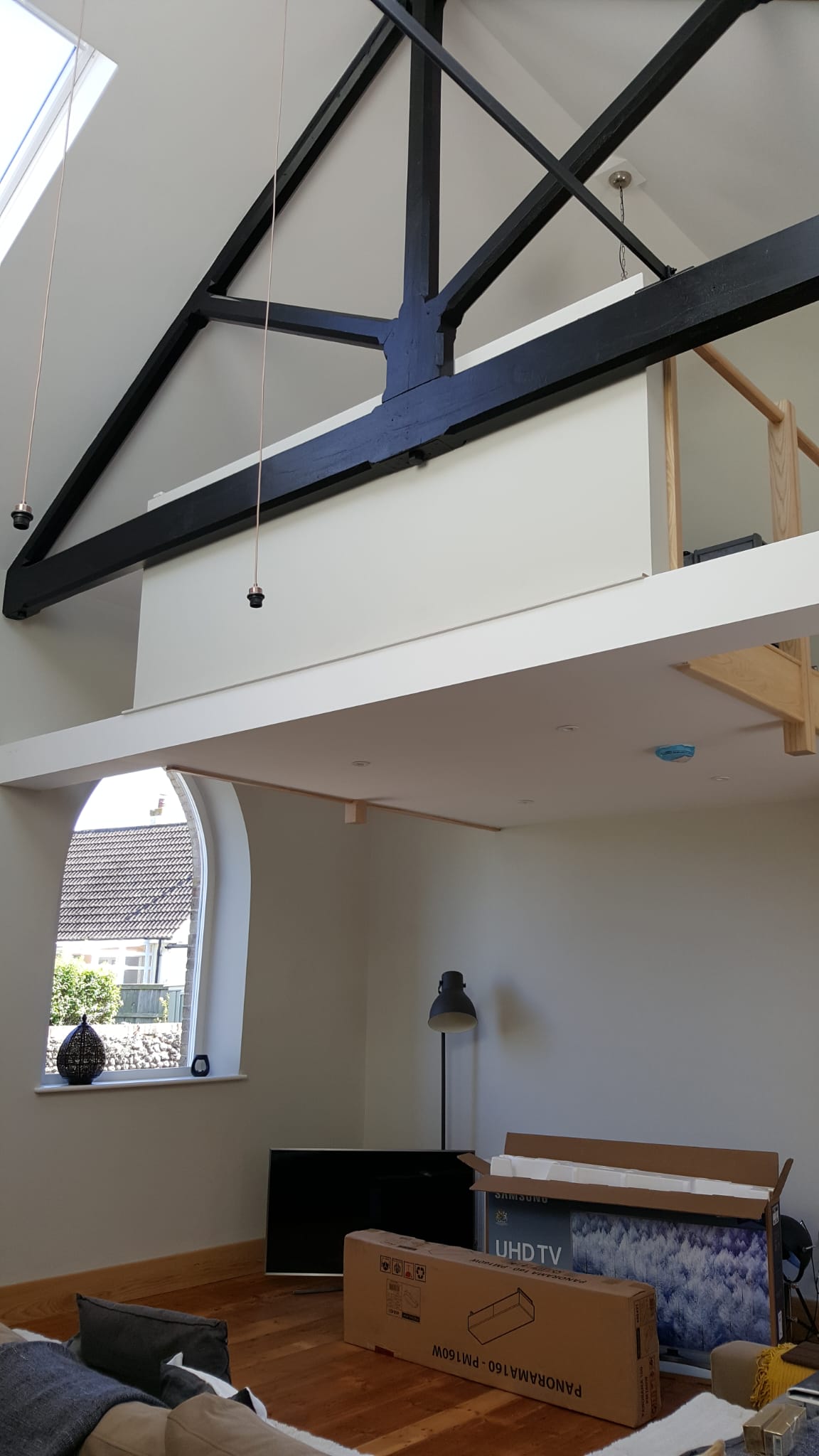 Vaulted ceiling with exposed steel trusses and mezzanine in a converted barn